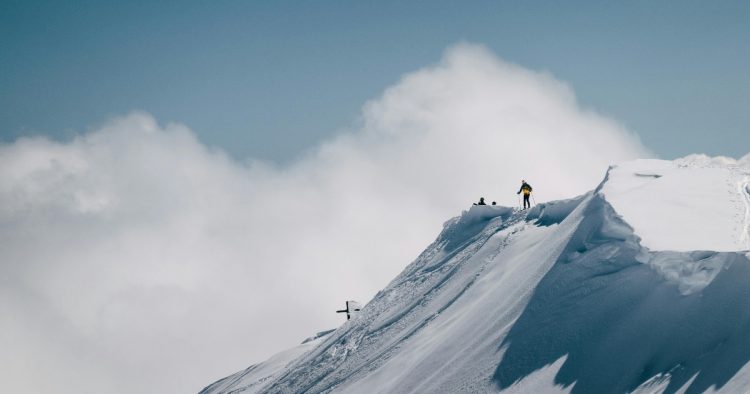 Mountaineers standing on a snowy mountain peak summit, representing career achievement and retaining top talent.