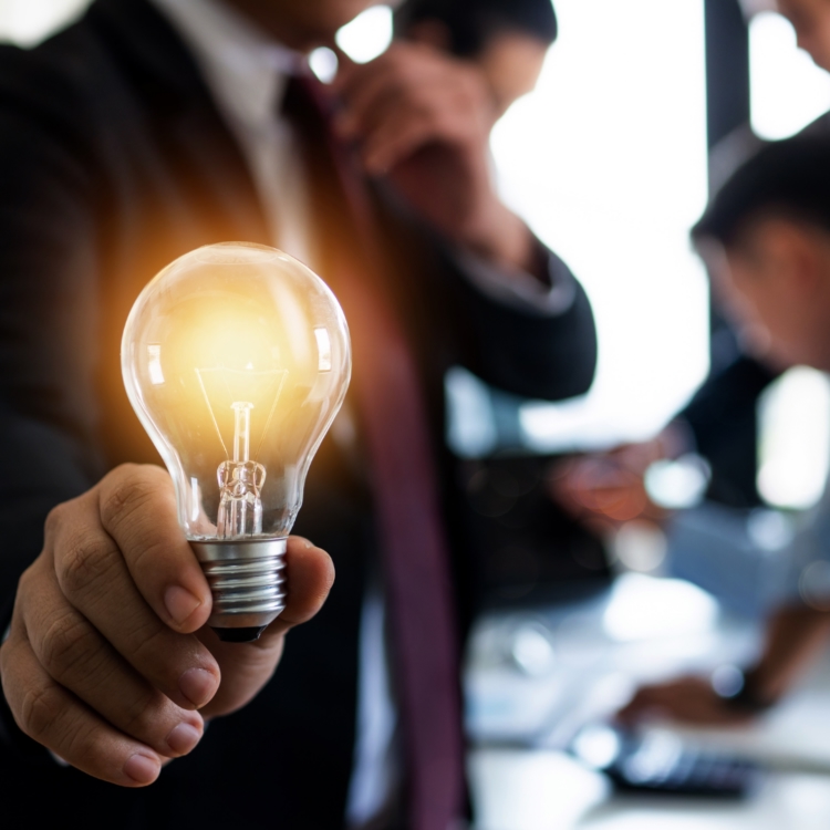 A business executive holding an illuminated lightbulb, representing career breakthrough and financial clarity in sales.