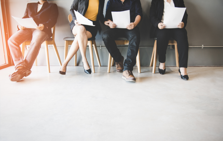 A group of people sat in a row holding papers