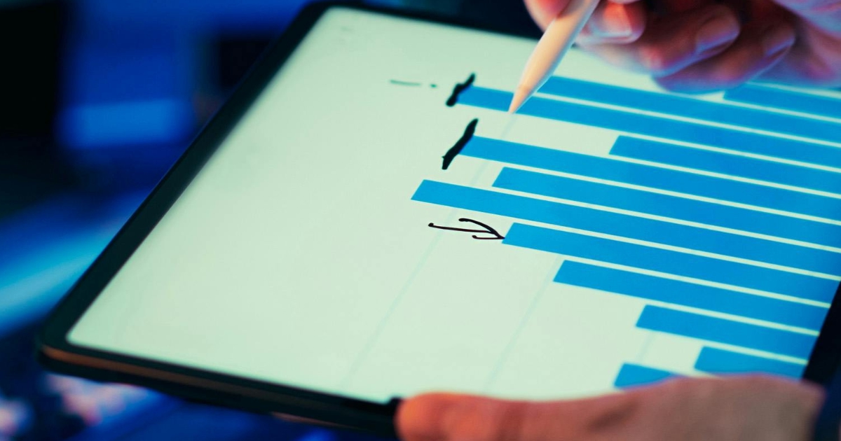 A hiring manager using a digital stylus to analyze recruitment data and conversion bar charts on a tablet screen.