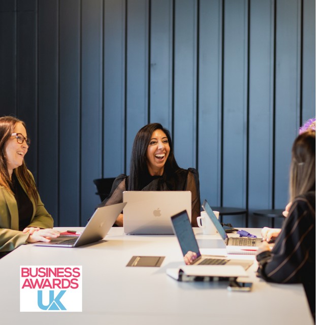 A group of women sat around a table with large tables with Business Awards UK logo