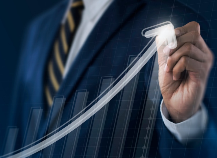 A business professional pointing to a rising growth arrow on a sales performance chart.