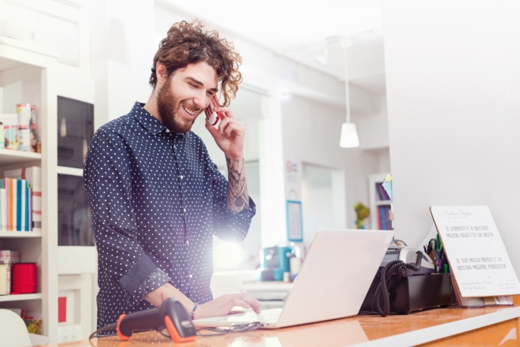 A sales professional talking on the phone while working on a laptop, demonstrating direct sales work-life balance.