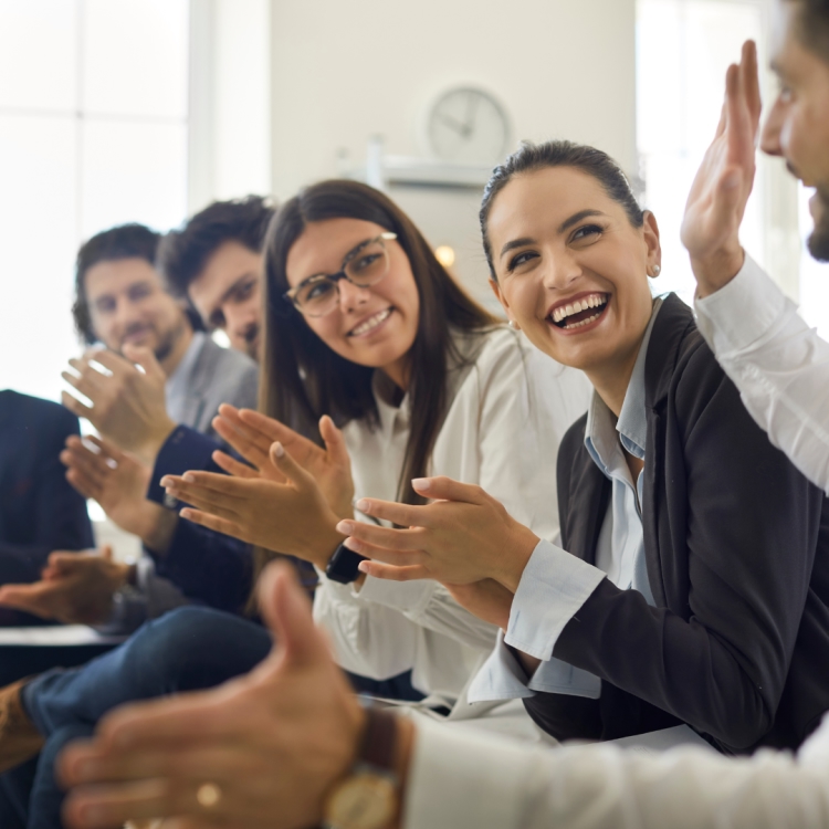 A resilient team of local sales professionals smiling and clapping together during a business meeting.