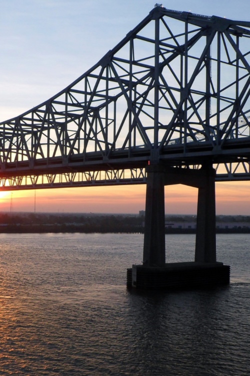 A solid steel bridge spanning a river at sunset, representing a structured sales career ladder built for long-term retention.