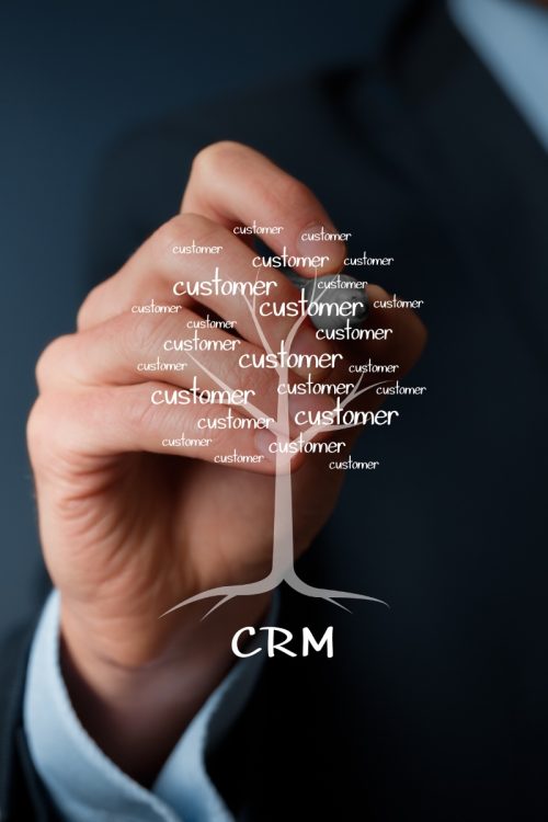 A hand drawing a customer growth tree rooted in CRM software, illustrating the best CRMs for small sales teams.