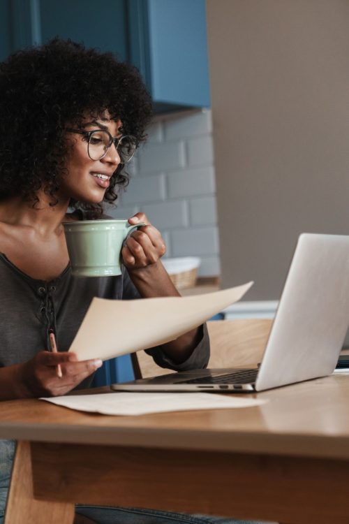A professional woman smiling and looking at her laptop screen with an engaged posture, demonstrating strong body language over Teams.