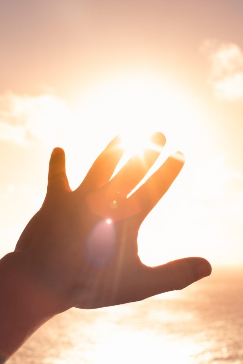 A silhouette of a hand reaching toward the bright sun, representing scaling revenue potential when you hire freelance sales agents.