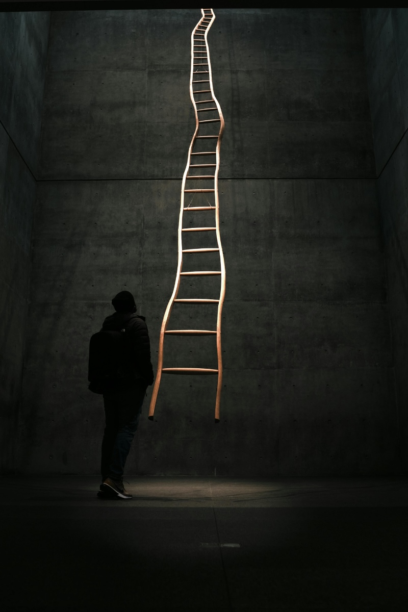 A person looking up at a tall wooden ladder, representing career progression when using sales to start a business.