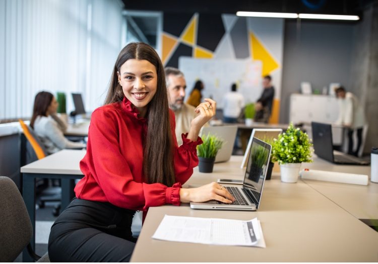 A sales manager working on a laptop in a modern open-plan office, representing scaling sales teams without losing quality.