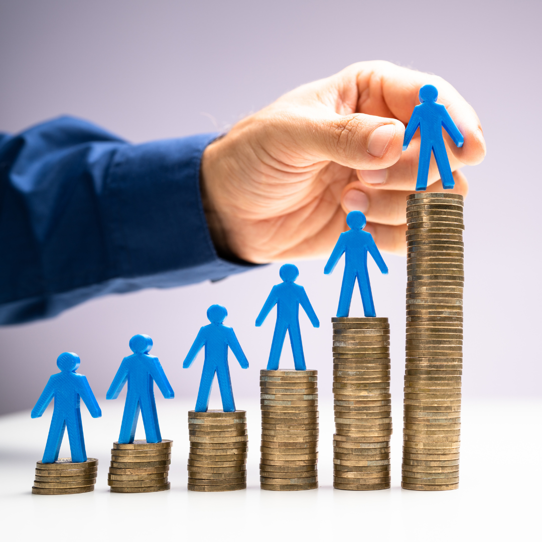 A hand placing blue human figures onto growing stacks of gold coins, symbolizing commercial growth and revenue generation.