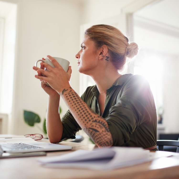 A consumer reflecting on a purchasing decision while sitting at her home desk.
