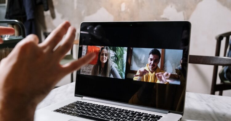 A laptop screen displaying a hybrid video conference call with remote team members collaborating during a virtual meeting.