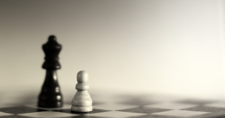 A white pawn standing next to a black queen on a chessboard, representing strategic recruitment and talent positioning.