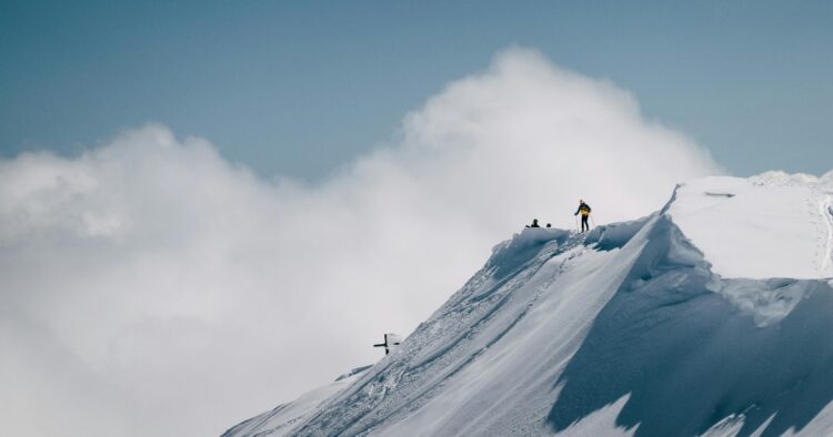 Mountaineers standing on a snowy mountain peak summit, representing career achievement and retaining top talent.