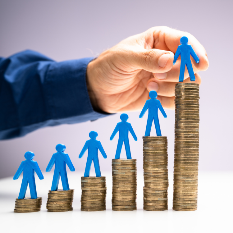 A hand placing blue human figures onto growing stacks of gold coins, symbolizing commercial growth and revenue generation.