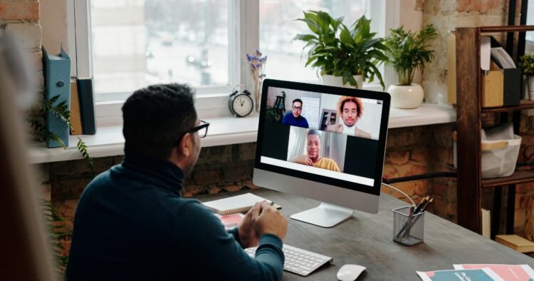 A professional candidate sitting at a home office desk conducting an online virtual interview on a desktop computer.