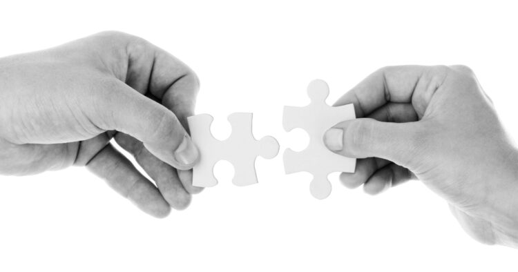 Two hands fitting matching puzzle pieces together, representing finding the right match between candidates and employers.